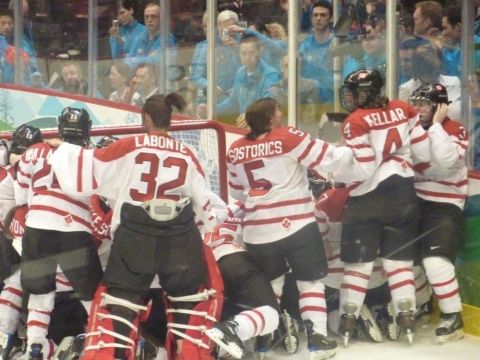 1996 Ford Bronco - A group of Canadian women's hockey players celebrate a victory on the ice, with spectators visible behind the glass.
