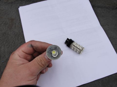 1995 Ford Bronco - A hand holds a silver-based LED bulb, with a second LED bulb resting on a document.