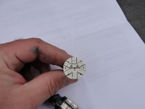 1995 Ford Bronco - A hand holds an LED bulb that features a swastika symbol in its center.