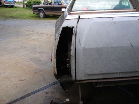 1973 Ford Ranchero - The rear quarter panel of a pickup truck shows significant rust and damage around the wheel well.