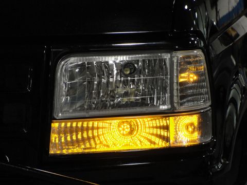 1995 Ford Bronco - The front passenger side headlight and turn signal assembly of a black vehicle is shown in detail.