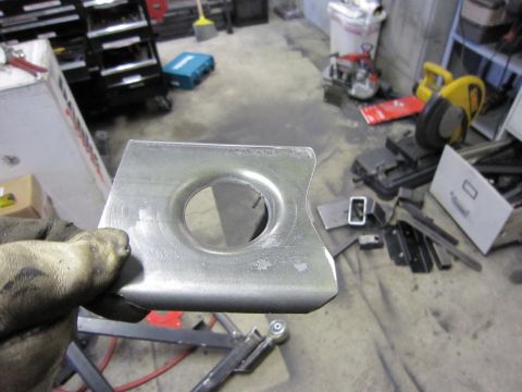 1996 Ford Bronco - A metal bracket with a hole is held up in a workshop environment.