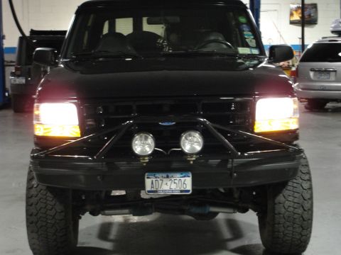 1995 Ford Bronco - 1995 Ford Bronco front view, showing custom bumper and lights. Another vehicle is visible in the background.
