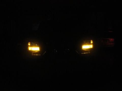 1995 Ford Bronco - The front of a vehicle is visible at night, with its amber turn signals illuminated.