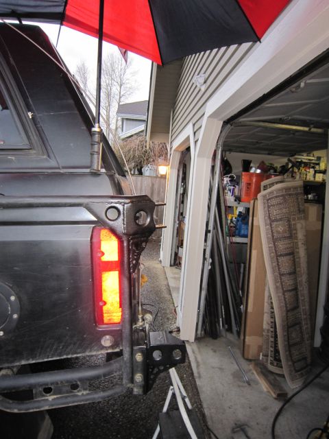 1996 Ford Bronco - The rear of a truck is visible, parked beside a garage filled with various items.