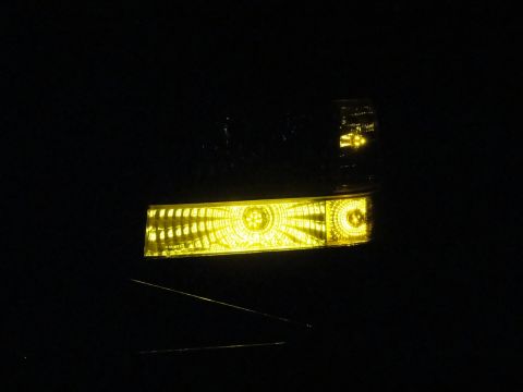 1995 Ford Bronco - Close-up of illuminated yellow headlights on a vehicle at night.