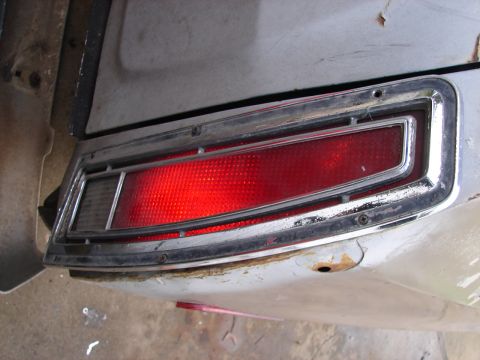1973 Ford Ranchero - Tail light assembly with chrome trim, showing rust on the body panel.