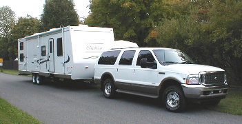 2000 Ford Excursion - A white 2000 Ford Excursion is shown towing a large travel trailer down a road.