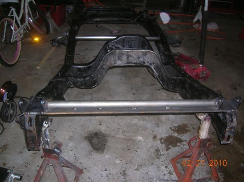 1985 Ford Bronco - A vehicle frame is supported by jack stands in a garage, with a date stamp visible in the lower right corner.