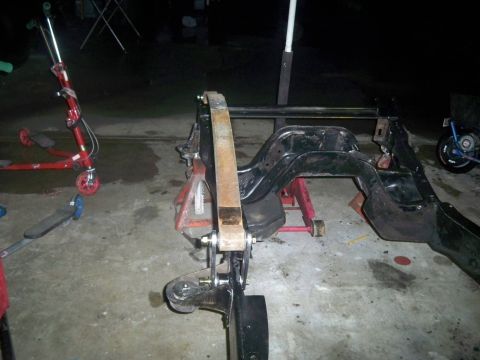 1985 Ford Bronco - The frame of a vehicle is supported by jack stands, showing the leaf spring and suspension components.