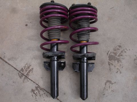1995 Ford Taurus - Two front struts with purple coil springs are displayed on a concrete floor.
