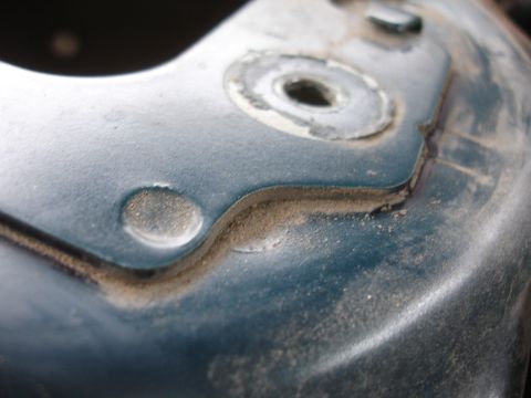 1995 Ford Taurus - A detailed view of a dusty, teal-colored metal component, likely from a vehicle's suspension system.