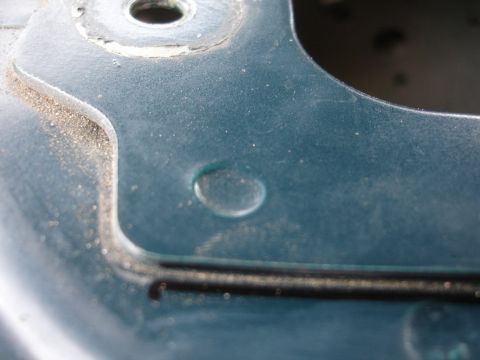 1995 Ford Taurus - Close-up view of a teal painted metal component, showing a circular indentation and a recessed channel.