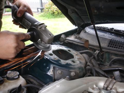 1995 Ford Taurus - Grinding sparks fly from the strut tower in a vehicle's engine bay.