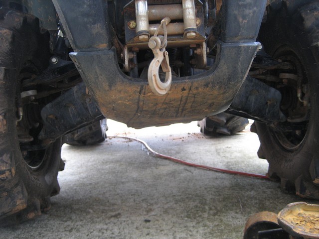 All-terrain vehicle undercarriage with winch and hook, showing large tires and suspension components