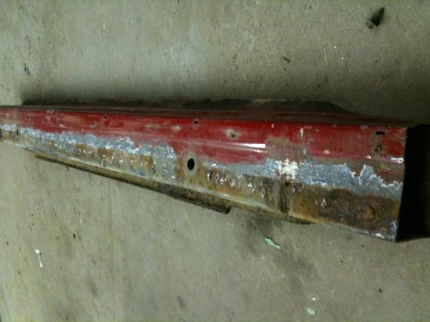 1993 Ford Bronco - A heavily rusted red metal rocker panel is shown, indicating significant wear and tear.