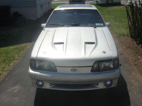 1987 Ford Mustang - A silver 1987 Ford Mustang is parked in a driveway, facing the camera.