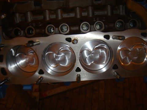 1987 Ford Mustang - Close-up view of engine pistons within a block, showing machined surfaces and valve reliefs.