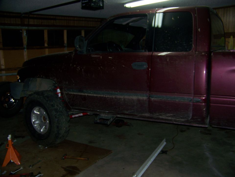 Side view of a red 2001 Dodge 1500 pickup truck with a lift kit installed