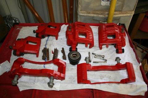 2007 Ford Mustang - Several red brake calipers and associated hardware are arranged on a table.