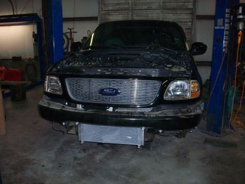 2007 Ford Mustang - Front view of a black Ford F-150 truck in a garage, with its hood up and an intercooler installed.