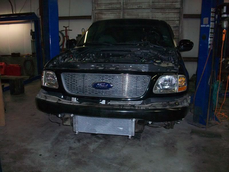 Black Ford F-150 truck with hood open, front grille, and aftermarket intercooler visible