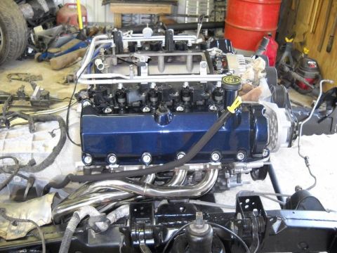 2007 Ford Mustang - A disassembled engine with custom headers sits in a garage, awaiting reassembly.