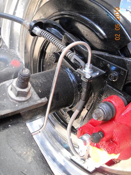 2007 Ford Mustang - Close-up view of a vehicle's rear brake caliper and drum assembly, a red caliper and silver brake line.