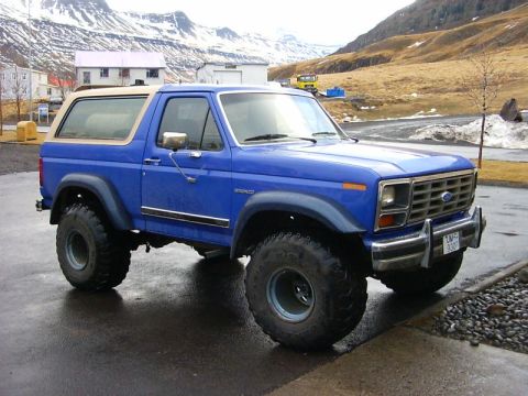 1986 Ford Bronco - This blue 1986 Ford Bronco features a tan removable top and large off-road tires.