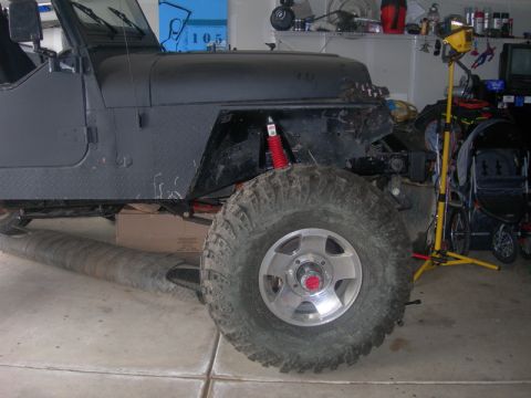 1991 Jeep Wrangler - Front view of a 1991 Jeep Wrangler showing the fender, large tire, and red shock absorber.