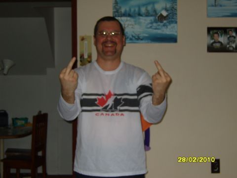 1989 Ford Bronco - A man stands indoors, wearing a shirt with a Canadian theme and giving the middle finger with both hands.