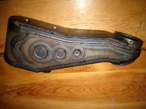1996 Ford Bronco - A custom-fabricated metal part, likely for a vehicle's steering system, is shown against a wooden background.