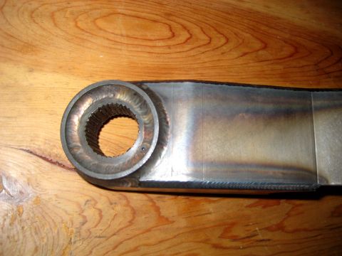 1996 Ford Bronco - Close-up of a metal suspension component with a splined opening, resting on a wooden surface.