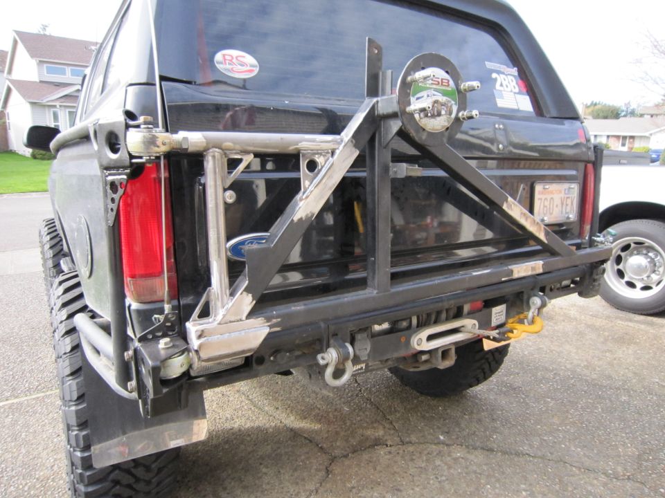 Rear view of black SUV with custom bumper, spare tire mount, and winch