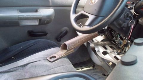 1979 Chevrolet Blazer - The interior of a vehicle shows a steering wheel, exposed wiring, and a crude metal steering column lock device.