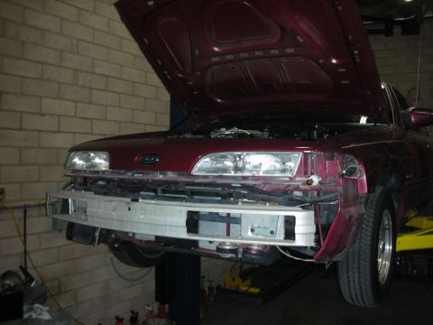 1992 Ford Crown Victoria - Front view of a 1992 Ford Crown Victoria on a lift with its hood open and bumper removed, revealing the intercooler project.
