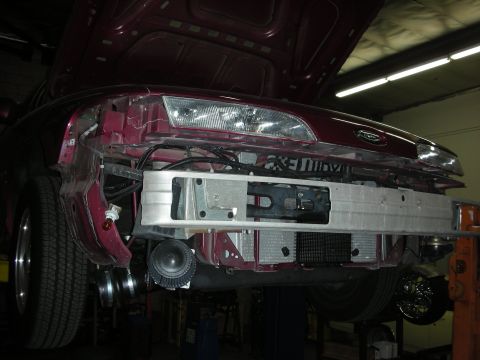 1992 Ford Crown Victoria - The front of a car is disassembled in a garage, revealing its internal components and intercooler system.