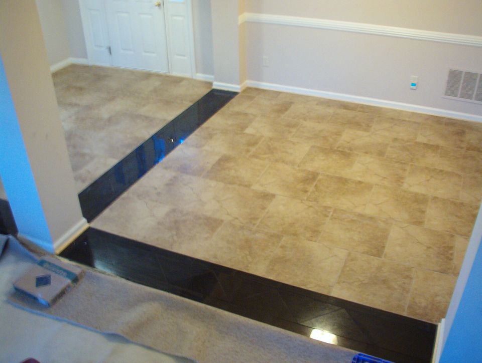 Newly laid beige tile dining room floor with dark glossy border edging a step