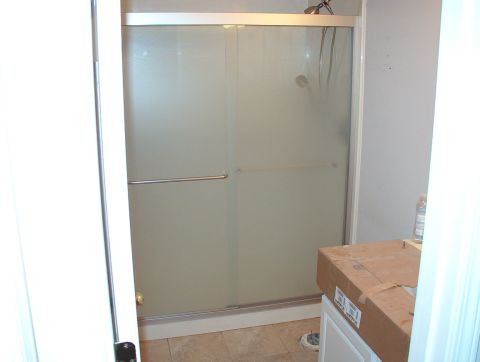 2004 Land Rover Land Rover - A bathroom scene a shower stall with frosted glass doors and a cardboard box on a vanity.