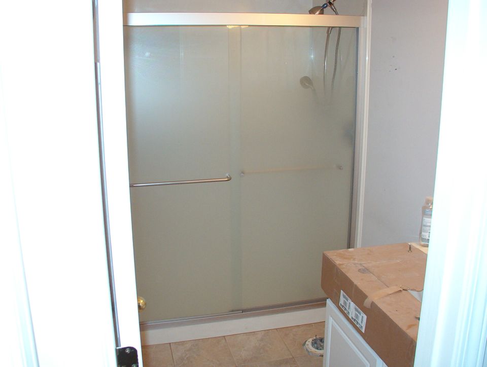 Bathroom remodel with frosted glass sliding shower door and boxed vanity top