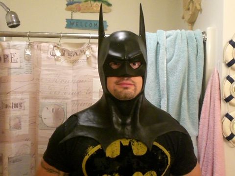 1995 Ford Probe - Person in Batman costume in a bathroom with shower curtain and towels visible.