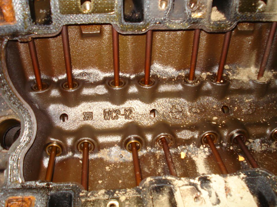 Close-up of an engine block showing pushrods and some stamped numbers like '351 WCP-12'