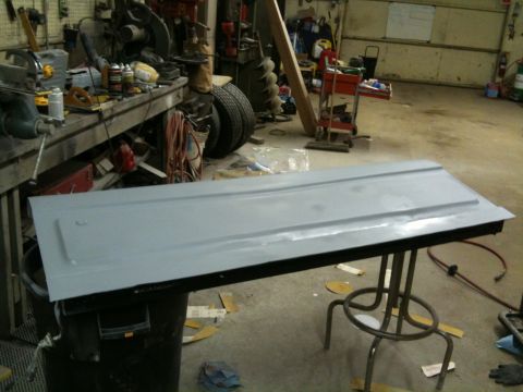 1993 Ford Bronco - A gray tailgate rests on a table in a workshop, surrounded by tools and automotive parts.