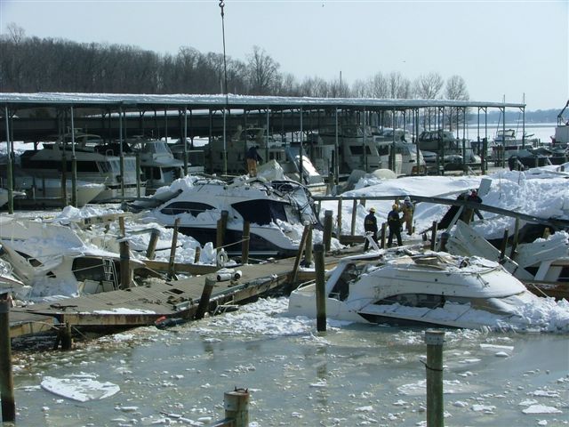 Boats damaged and covered in snow at a frozen marina