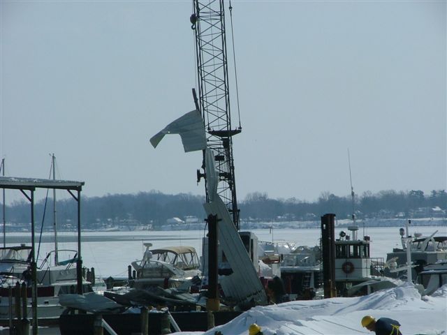 Crane wreckage and boats covered in snow at a frozen marina