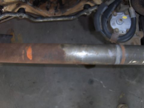 1971 Chevrolet Camaro - Underside view of a vehicle's driveshaft and a hydraulic component, showing some rust and an orange paint mark on the driveshaft.