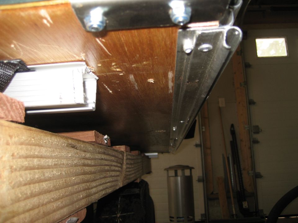 Trailer frame with wooden supports and metal brackets, viewed from below