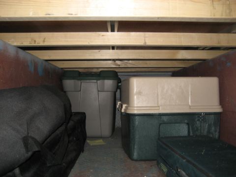 1996 Ford Bronco - Various storage containers are visible inside a trailer, with wooden beams forming the ceiling.