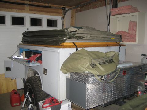 1996 Ford Bronco - Custom truck bed camper shell with storage and a tent is parked inside a garage.