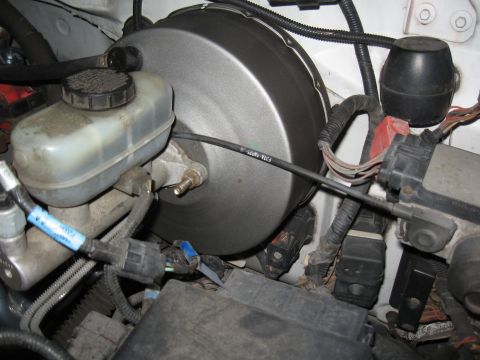1994 Ford Bronco - Close-up view of the brake booster and master cylinder assembly, showing various hoses and electrical connectors.